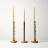 Three wooden candle holders with candles on a white background