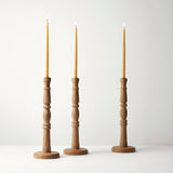 Three wooden candle holders with candles on a white background