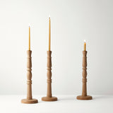 Three wooden candle holders with candles on a white background