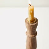 Beeswax candle in a wooden holder on a white background