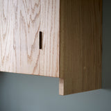 Close up of side of oak wall cabinet showing grain pattern and dowel jointing detail.