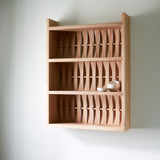 Shelve unit in ash wood. Three shelves. Woven wood back. Two ceramic dishes on shelf.