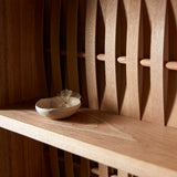 Close up of shelve unit in ash wood. Three shelves. Woven wood back. Small ceramic dish on shelf.