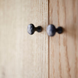 Close up of black steel hammered door knobs on grainy oak wood doors.