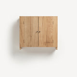 Close up of Oak cabinet with two doors, one open, and metal knobs. Pictured against blue wall. Open door reveals woven wood back,Oak wall cabinet with two doors with black metal door knobs.