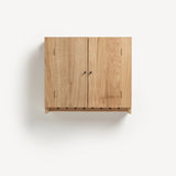 Oak cabinet with two doors and metal knobs. Shaker peg rail at bottom with black metal pegs.