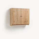 Oak cabinet with two doors and metal knobs. Shaker peg rail at bottom with black metal pegs.