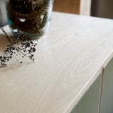 Top of cabinet showing detail of birch ply wood, green painted doors and glass vase with rope inside.
