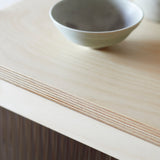 Top edge of cabinet with reeded glass and simple ceramic bowl on top. Detail of birch edge lamination.