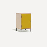 Single door ply wood contemporary bedside cabinet with bold yellow painted door, black metal door knobs and black metal legs. Shown at an angle.