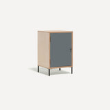 Single door ply wood contemporary bedside cabinet with blue grey painted door, black metal door knobs and black metal legs. Shown at an angle.