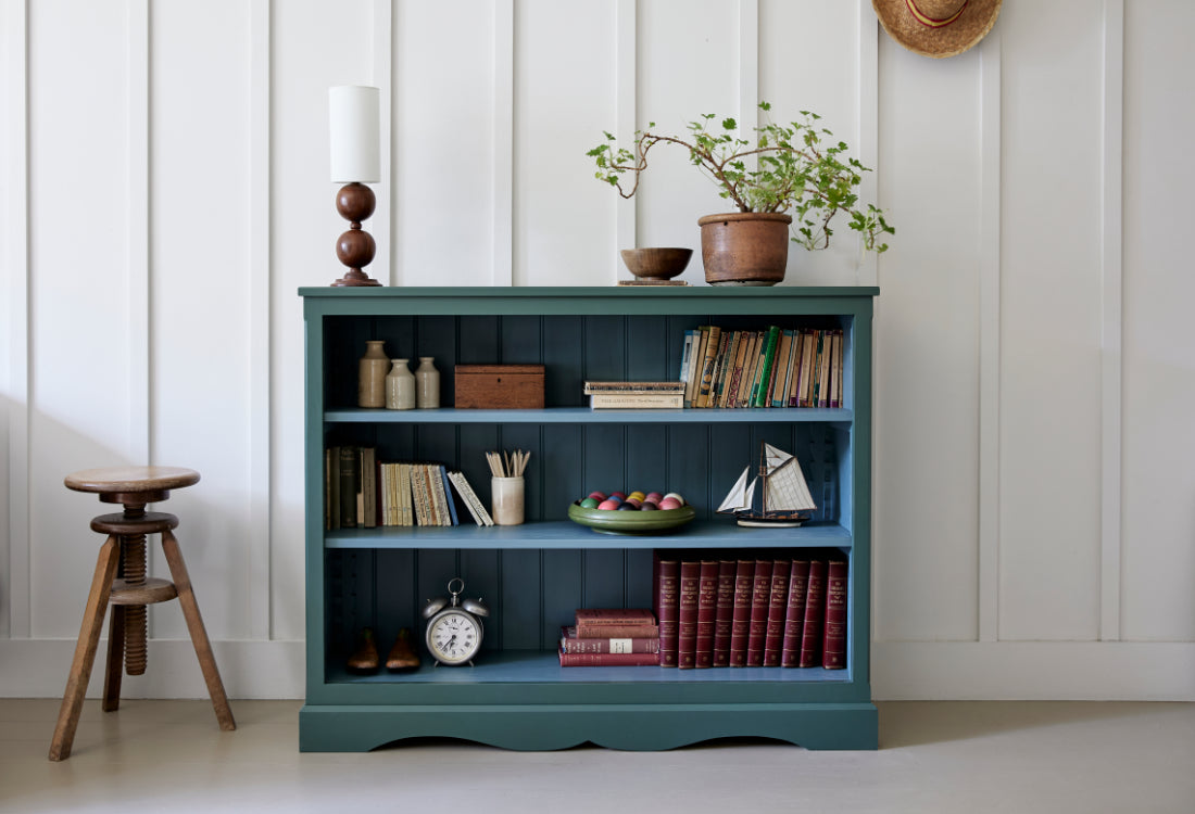 Blue bookshelf with decorative items against a white paneled wall.
