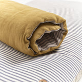 Close up of Dog bed topper cushion rolled up on floor cushion. Showing cotton ticking stripes and ochre linen.