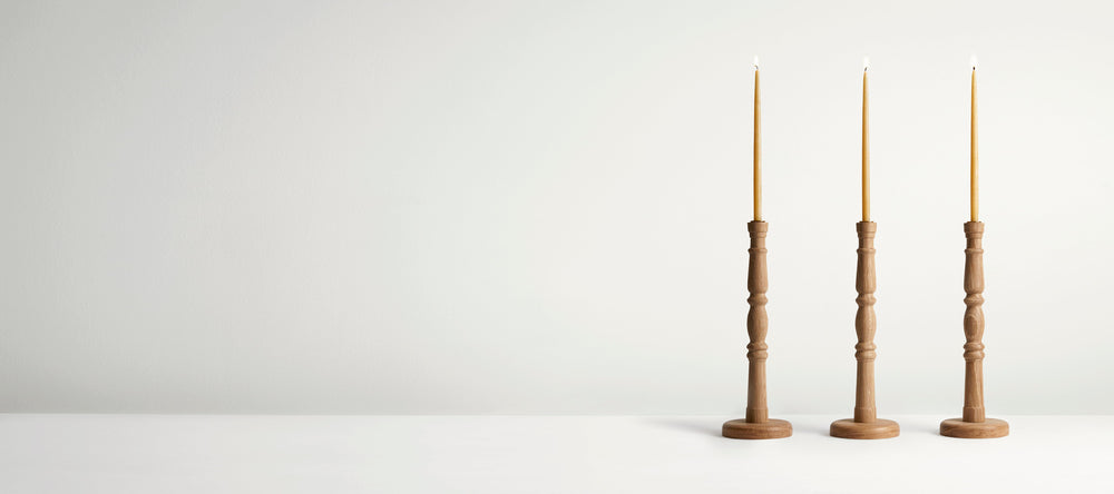 Three wooden candlesticks with candles on a white background