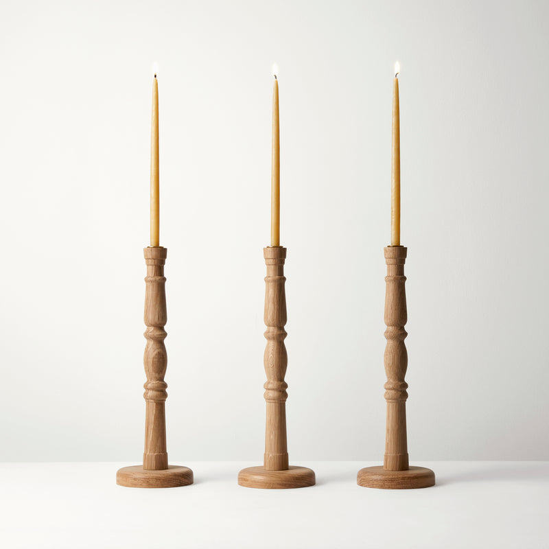 Three wooden candle holders with candles on a white background