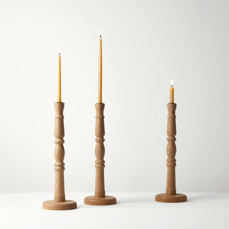 Three wooden candle holders with candles on a white background