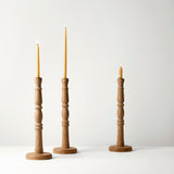Three wooden candle holders with candles on a white background