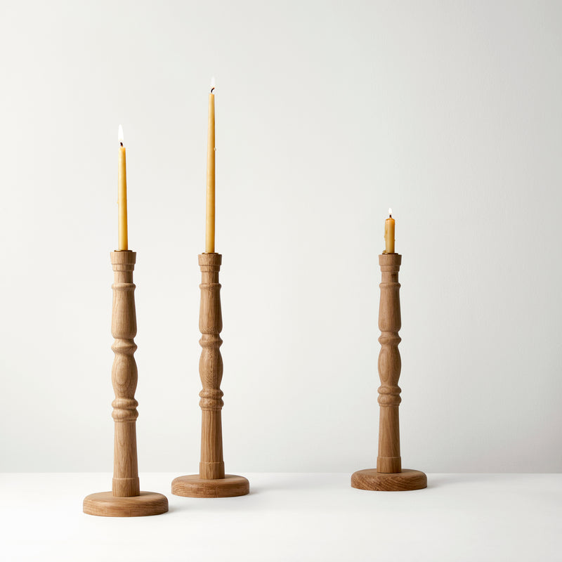 Three wooden candle holders with candles on a white background