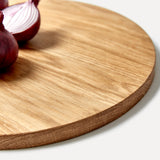 Round oak wood chopping board detail with red onions, one sliced