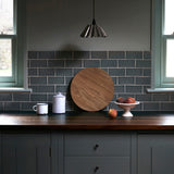 kitchen with blue tiles and walls, focussing on an oak chopping board with peaches in a bowl