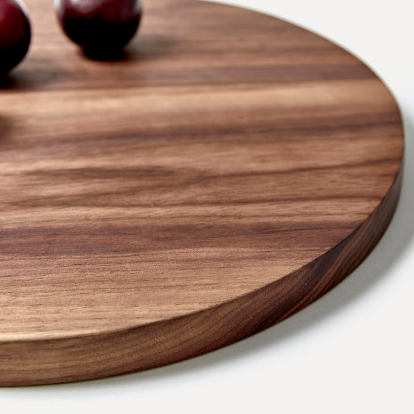 Round walnut wood chopping board with red onions on