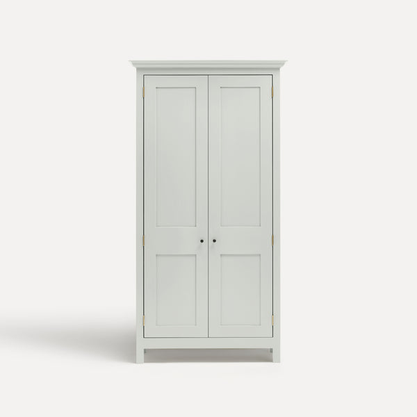 White painted freestanding tall cupboard Shaker style with panelled doors black metal knobs.