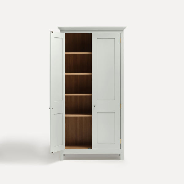 White painted freestanding tall cupboard Shaker style with panelled doors black metal knobs. One door open revealing oak interior and four shelves.