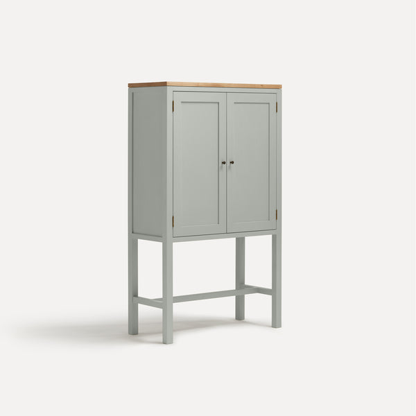 White painted two door shaker style cabinet on tall legs with oak work top. Shown at angle.