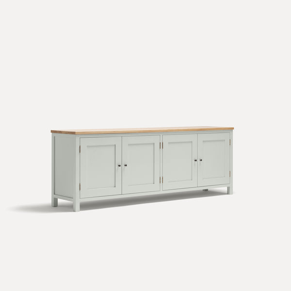 White painted four door shaker style sideboard with black metal door knobs and oak worktop. Shown at an angle.
