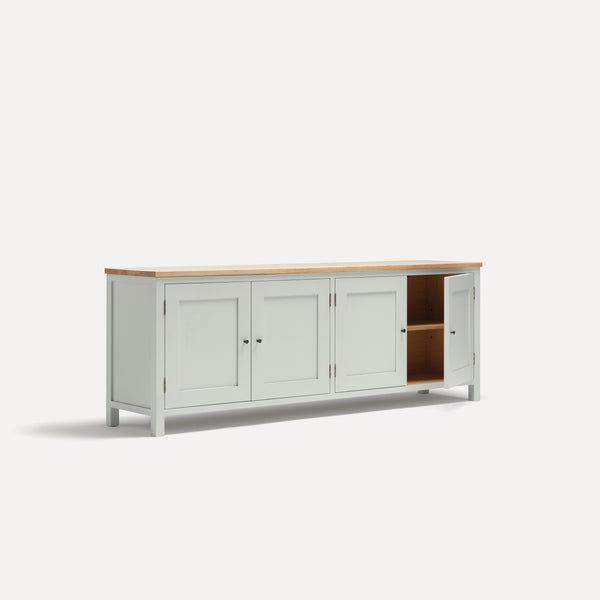 White painted four door shaker style sideboard with black metal door knobs and oak worktop. Shown at an angle with one door open.