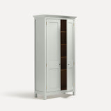 White painted freestanding tall cupboard Shaker style with panelled doors black metal knobs. Shown at an angle one door open.