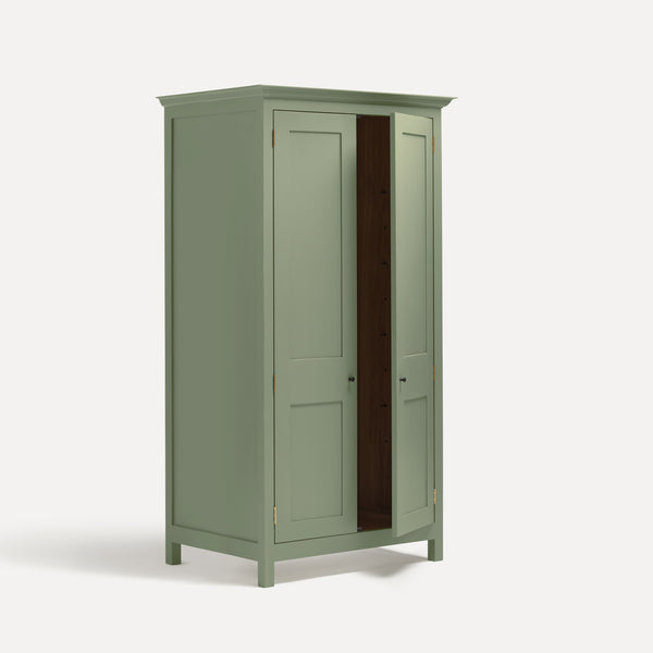 Green painted freestanding tall Armoire cupboard Shaker style with panelled doors and black metal knobs. Shown at angle with one door open.