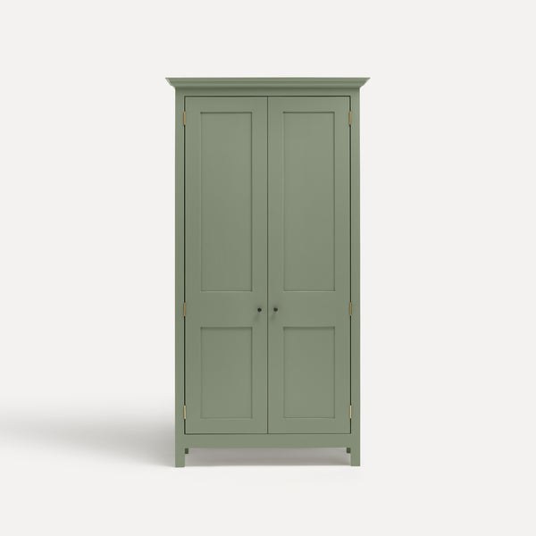Green painted freestanding tall Armoire cupboard Shaker style with panelled doors and black metal knobs. Shown face on with doors closed.