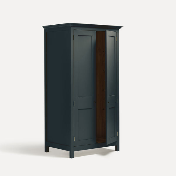 Dark Blue Grey painted freestanding tall Armoire cupboard Shaker style with panelled doors and black metal knobs. Shown at angle with one door open.