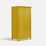 Yellow painted freestanding tall Armoire cupboard Shaker style with panelled doors and black metal knobs. Shown at angle with both doors closed.
