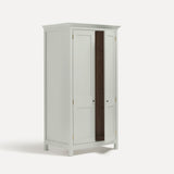 White painted freestanding tall Armoire cupboard Shaker style with panelled doors and black metal knobs. Shown at angle with one door open.