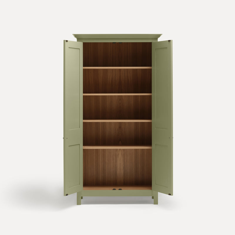 Tall freestanding wooden Shaker style two door cupboard with cornice and wooden legs, painted apple green. Two doors open revealing four shelves and oak interior.