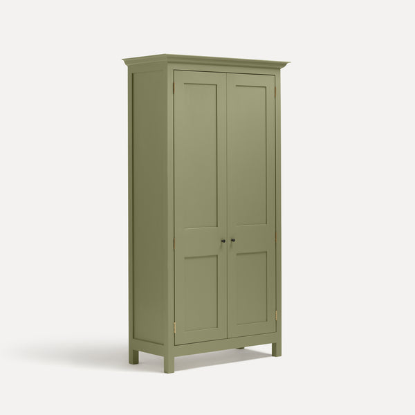 Tall freestanding wooden Shaker style two door cupboard with cornice and wooden legs, painted apple green.