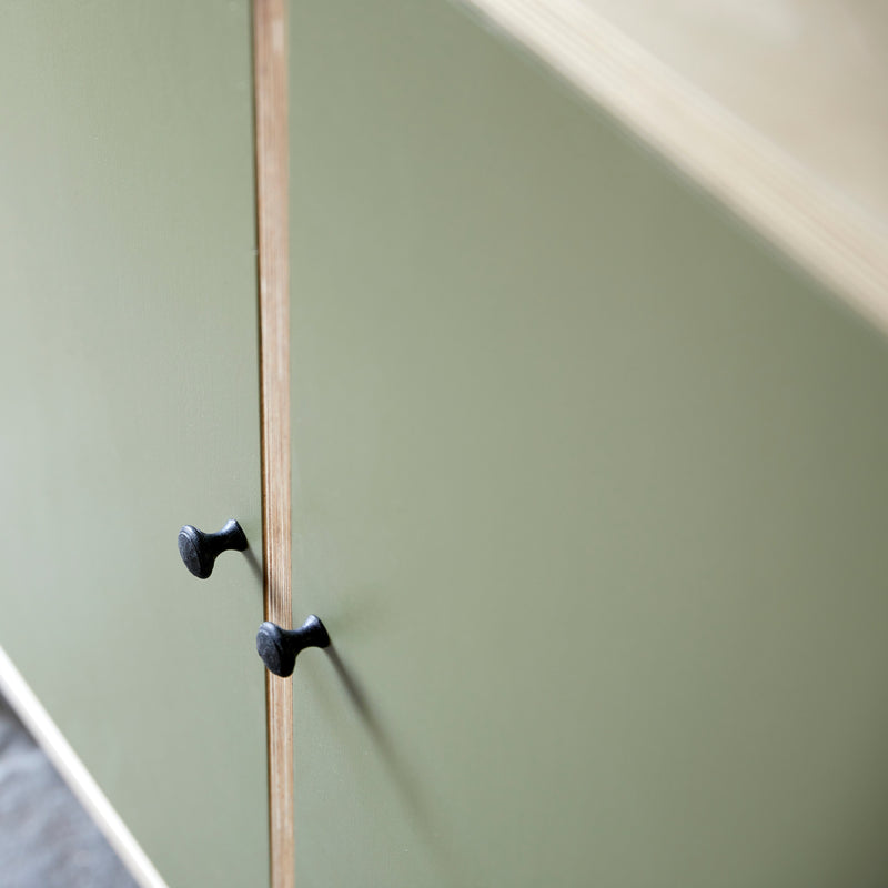 Close up of top corner of ply wood cabinet and green painted doors.