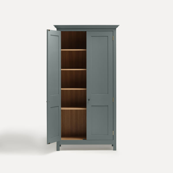 Blue Grey painted freestanding tall cupboard Shaker style with panelled doors black metal knobs. One door open showing oak interior and four shelves.