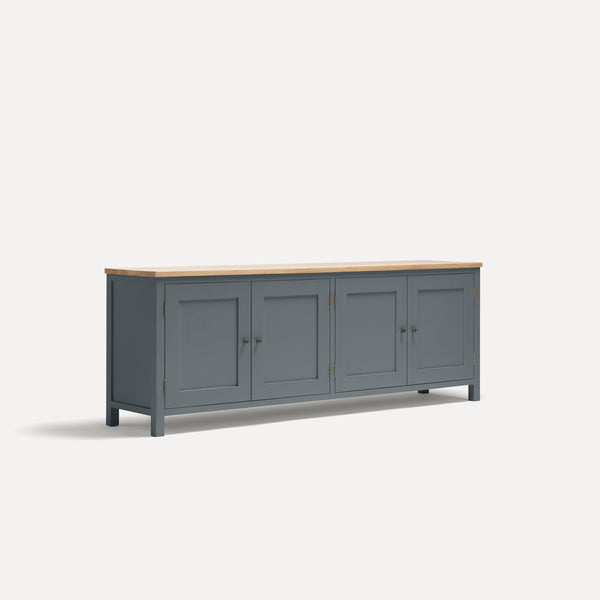 Blue painted four door shaker style sideboard with black metal door knobs and oak worktop. Shown at an angle.