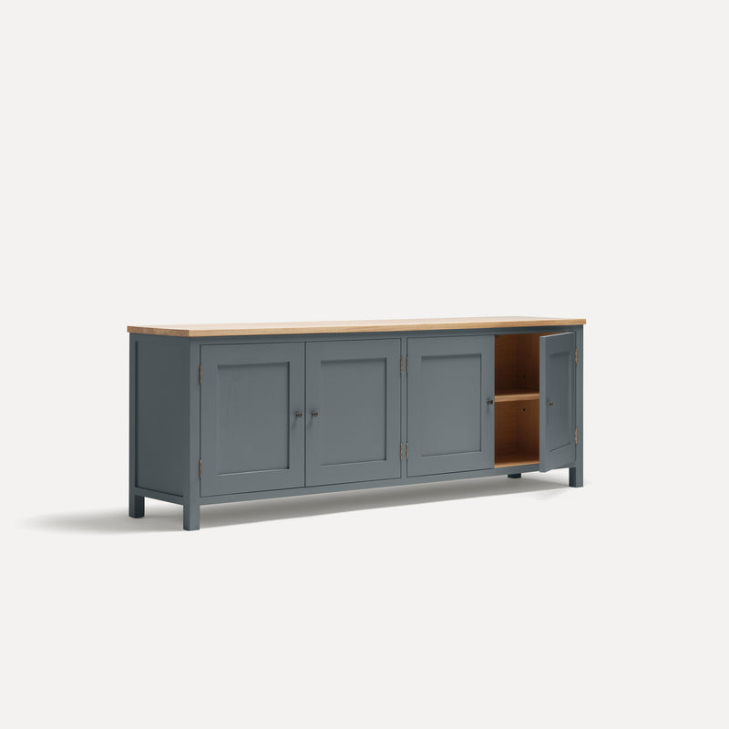 Blue painted four door shaker style sideboard with black metal door knobs and oak worktop. Shown at an angle with one door open.