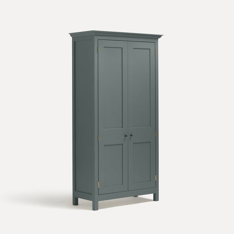 Blue Grey painted freestanding tall cupboard Shaker style with panelled doors black metal knobs. Shown at an angle.