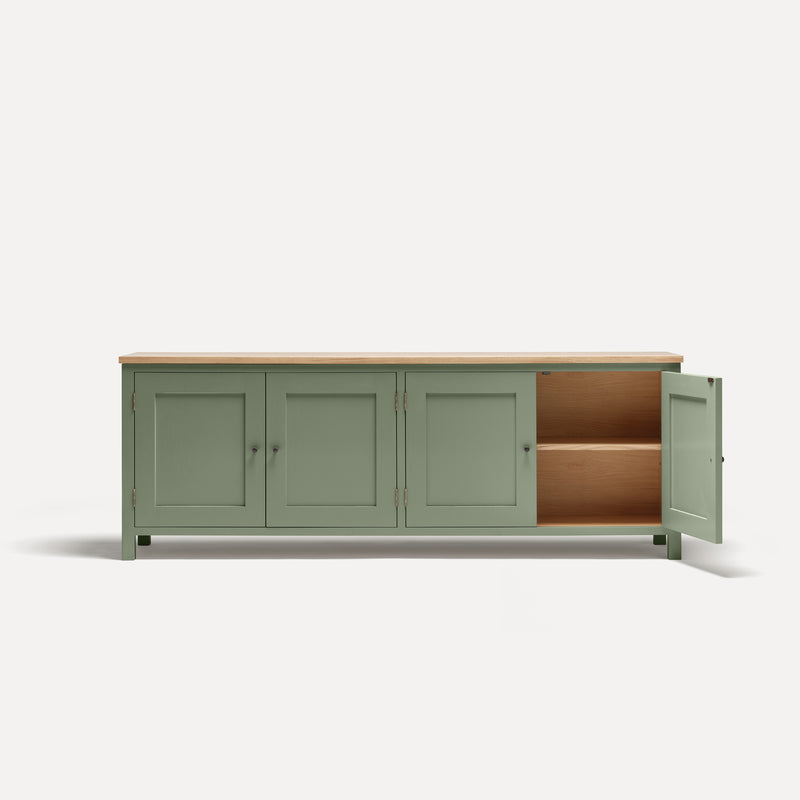 Green painted four door shaker style sideboard with black metal door knobs and oak worktop. One door open revealing oak interior and shelf.