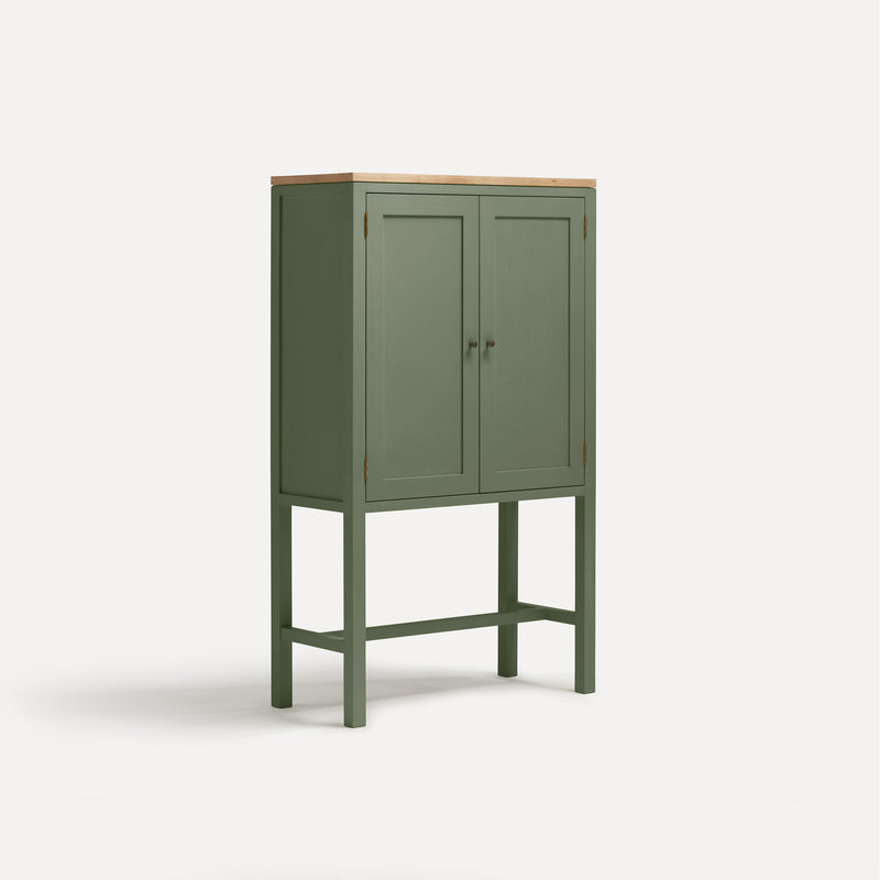 Green painted two door shaker style cabinet on tall legs with oak work top. Shown at angle.