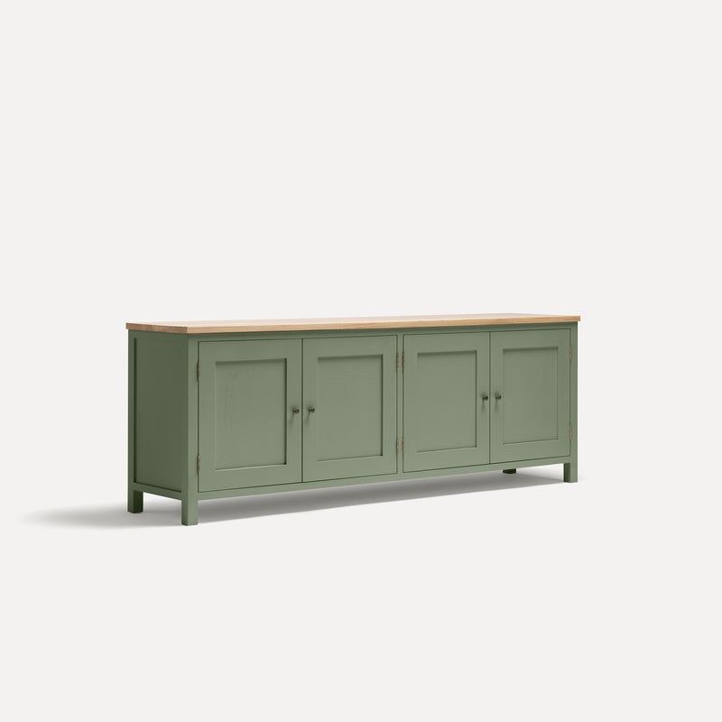 Green painted four door shaker style sideboard with black metal door knobs and oak worktop. Shown at an angle.