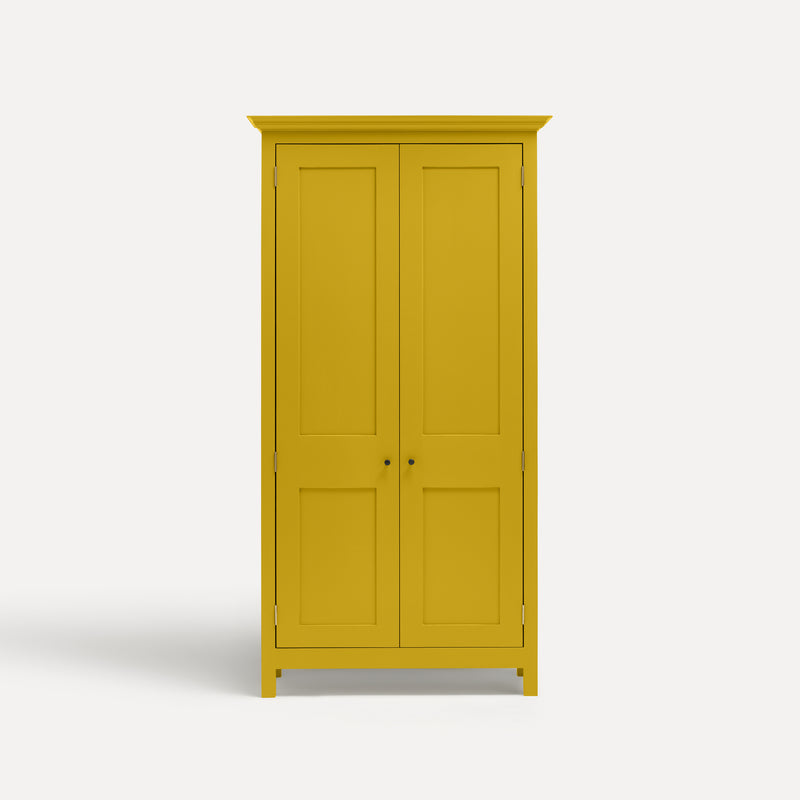Yellow painted freestanding tall cupboard Shaker style with panelled doors black metal knobs.