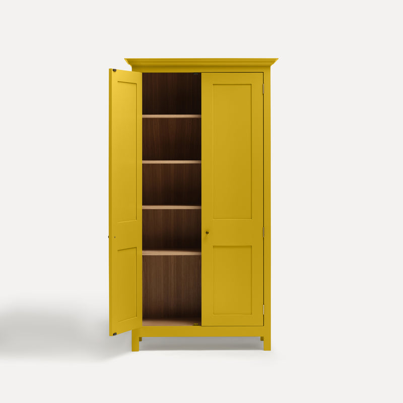 Yellow painted freestanding tall cupboard Shaker style with panelled doors black metal knobs. One door open revealing oak interior and four shelves.