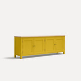 Yellow painted four door shaker style sideboard with black metal door knobs and oak worktop. Shown at an angle.