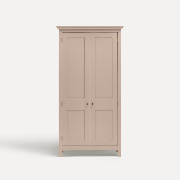 Pink painted freestanding tall cupboard Shaker style with panelled doors black metal knobs.